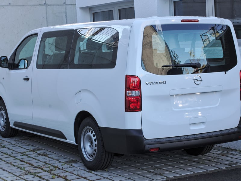 A white Opel Vivaro passenger minivan with side windows, the model of our eight-seat minivan